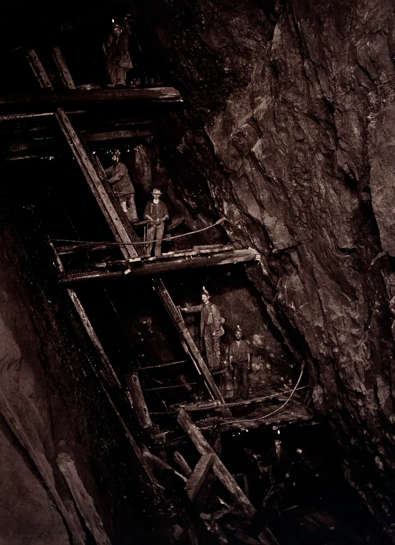 Miners on ladders and wooden platforms in Dolcoath tin mine, Cornwall