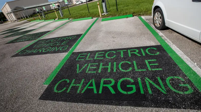 Electric vehicle charging bays painted on a car park, with a white car plugged in