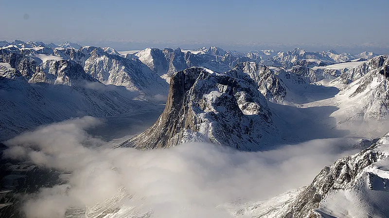 Snow-covered mountains rising from a dark, open fjord in south-west Greenland