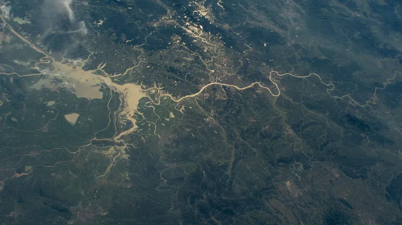Night-side view from orbit of a large city on a winding river among green hills in Hunan, China