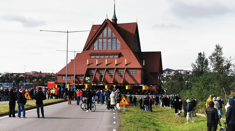 The church rolling along a widened road while a crowd walks behind it