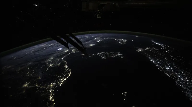 The lights of coastal cities around the western Mediterranean at night, seen from orbit, with stars above