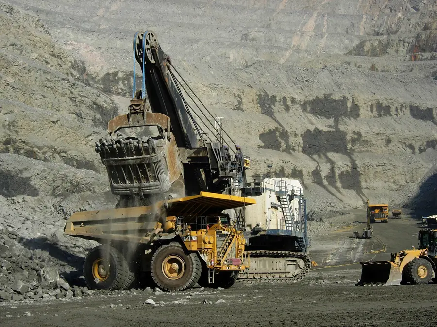 An electric rope shovel dumping rock into a haul truck on a bench of the Aitik copper pit