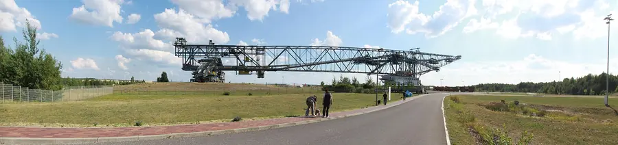 The F60 conveyor bridge at Lichterfeld, a steel lattice structure stretching across the horizon, with visitors on the road in front