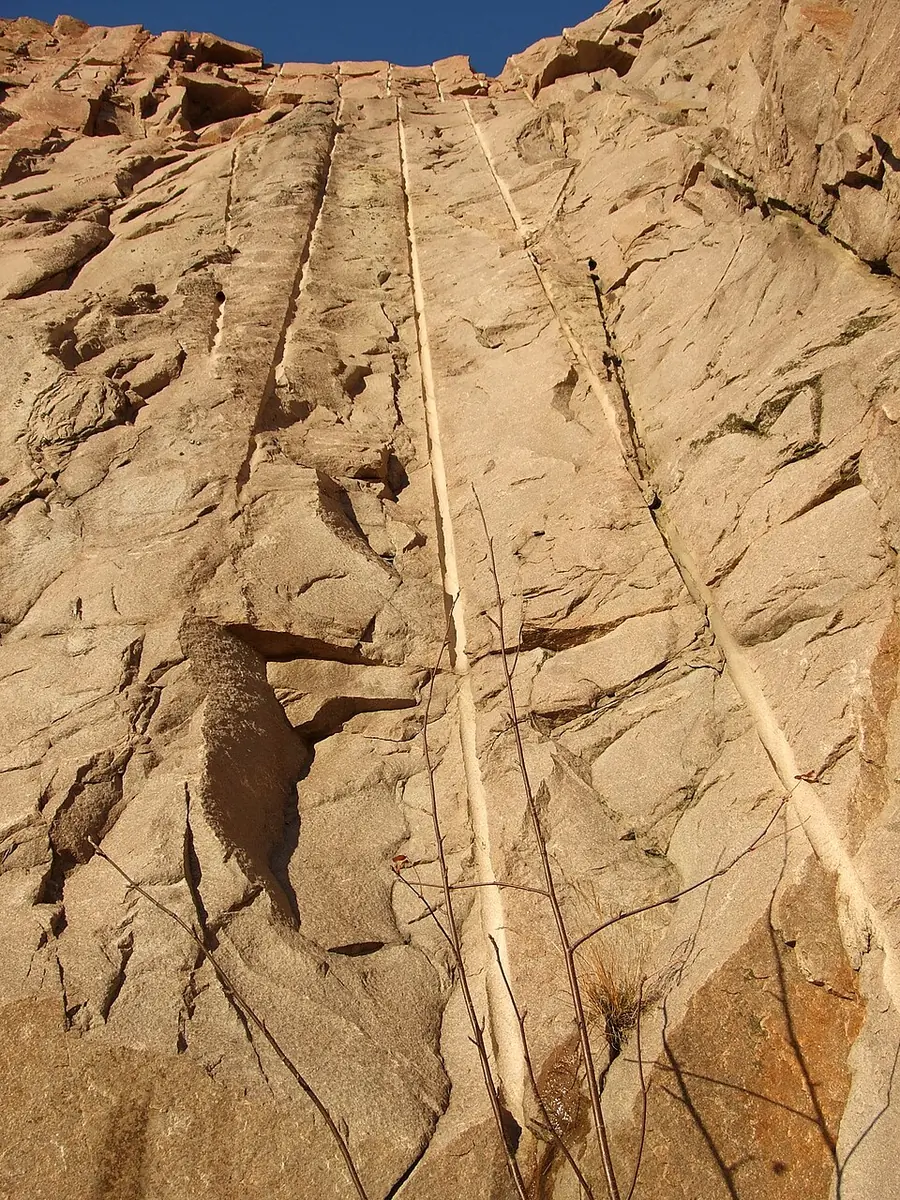 A granite quarry wall with the long half-cylinder traces of drilled blastholes running down it