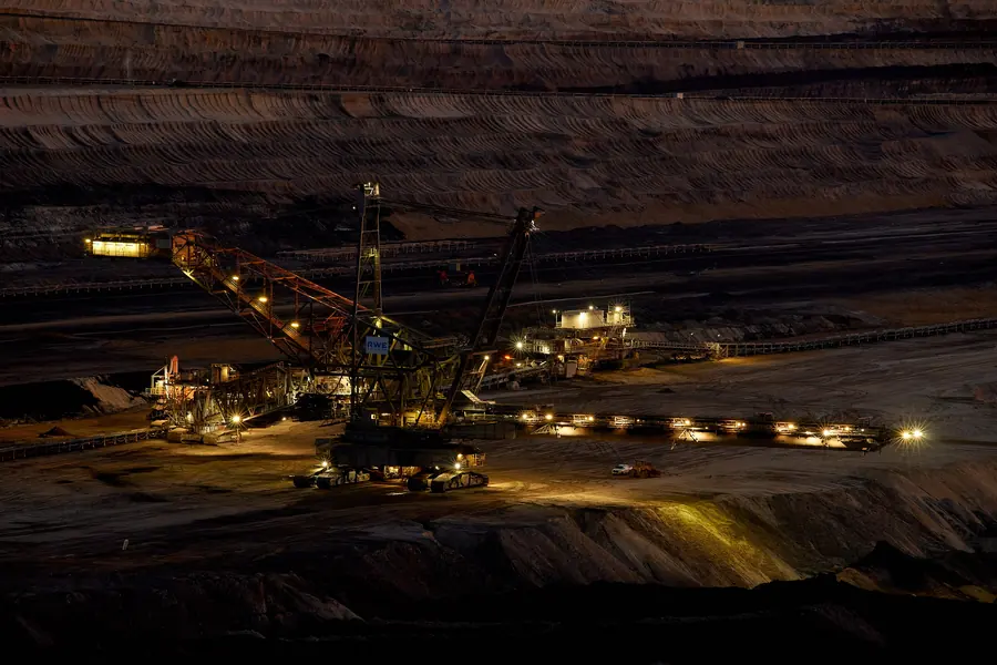 A spreader lit up at night in the Hambach pit, dropping spoil from the end of a long boom