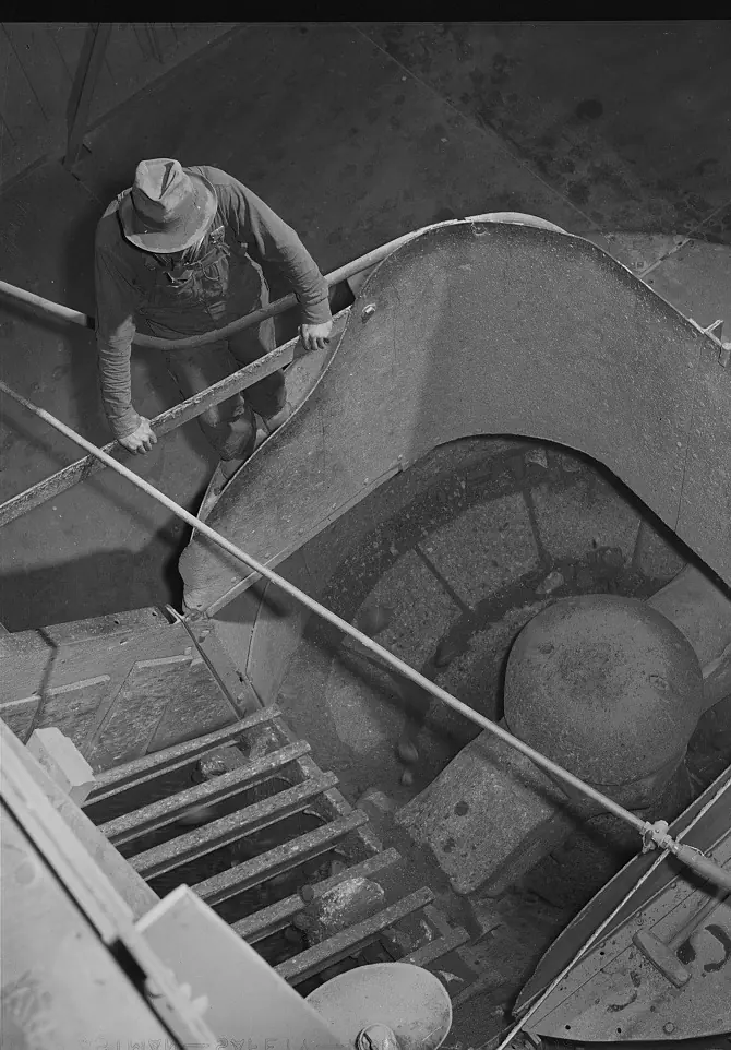 Looking down into the round hopper of a gyratory crusher, with a worker on the rim