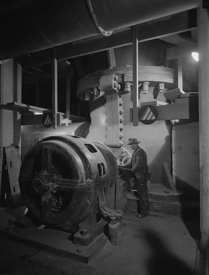 A worker beside the large electric motor that drives a gyratory crusher