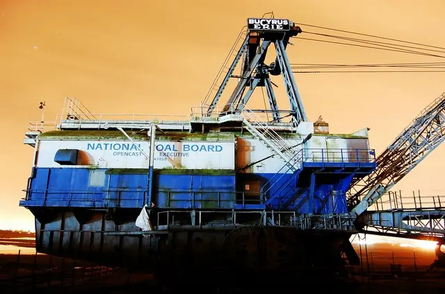 The blue and white house of a Bucyrus-Erie 1150 walking dragline, marked National Coal Board, against an orange sky