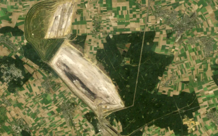 Hambach from space in 1985, a pit beside a large dark forest, and in 2025, the pit filling the land where most of the forest stood