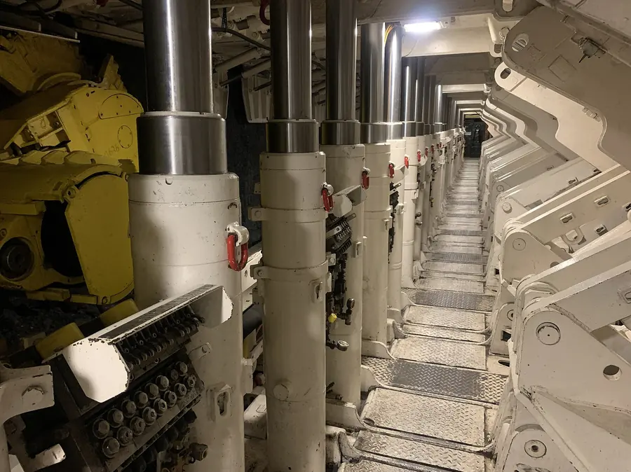 A walkway between rows of white hydraulic shield legs and canopies