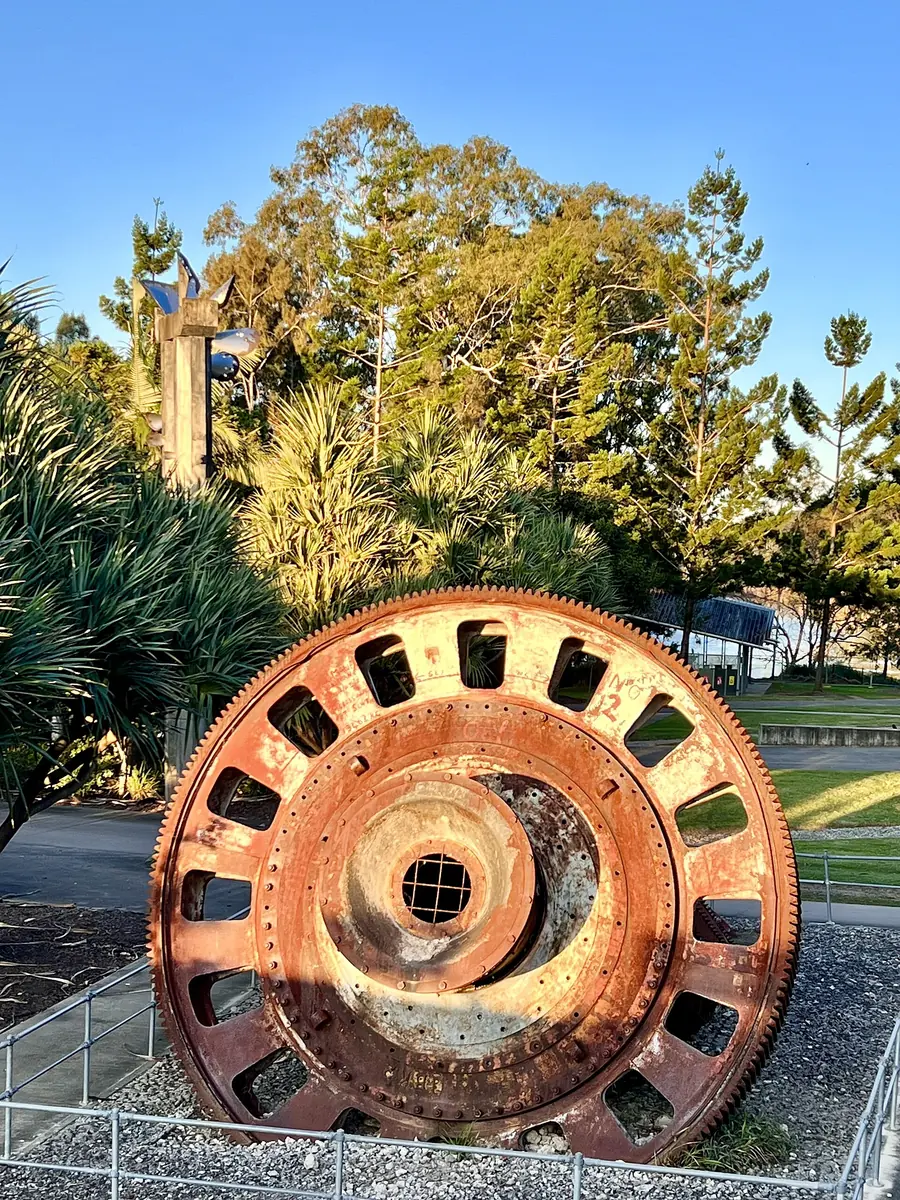 The rusted end of an old ball mill, with the big ring gear that turned it, on display in a park