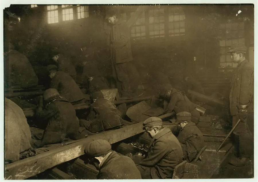 Boys hunched over coal chutes in a dusty, dim breaker