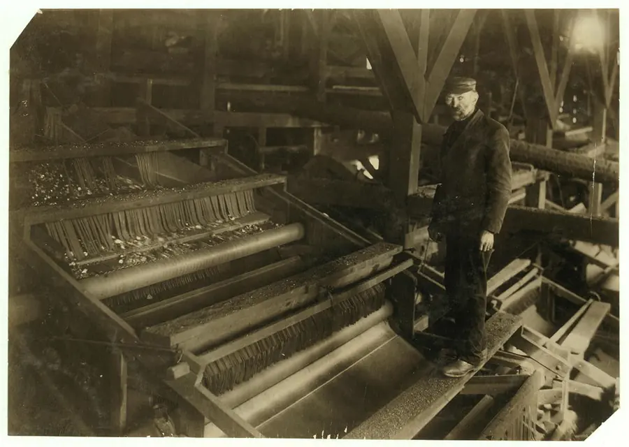 A man standing on a large coal-picking machine of slatted chutes