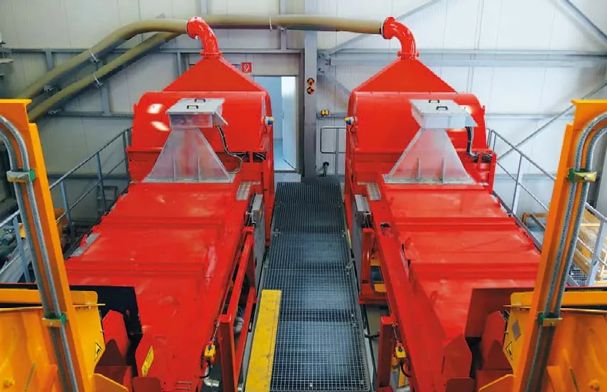 Two red belt-type ore sorters side by side in a plant building