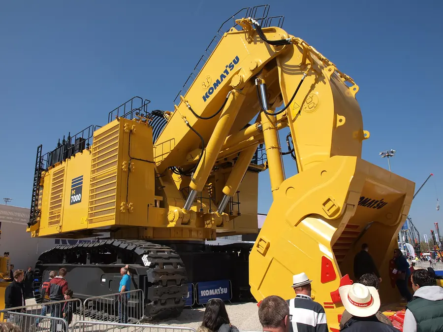 A giant yellow Komatsu mining excavator towers over visitors at an outdoor trade fair