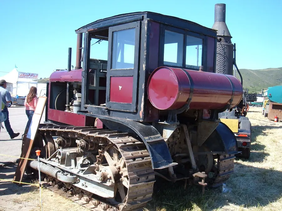 A red and black Caterpillar Sixty crawler tractor with a cab and tall exhaust