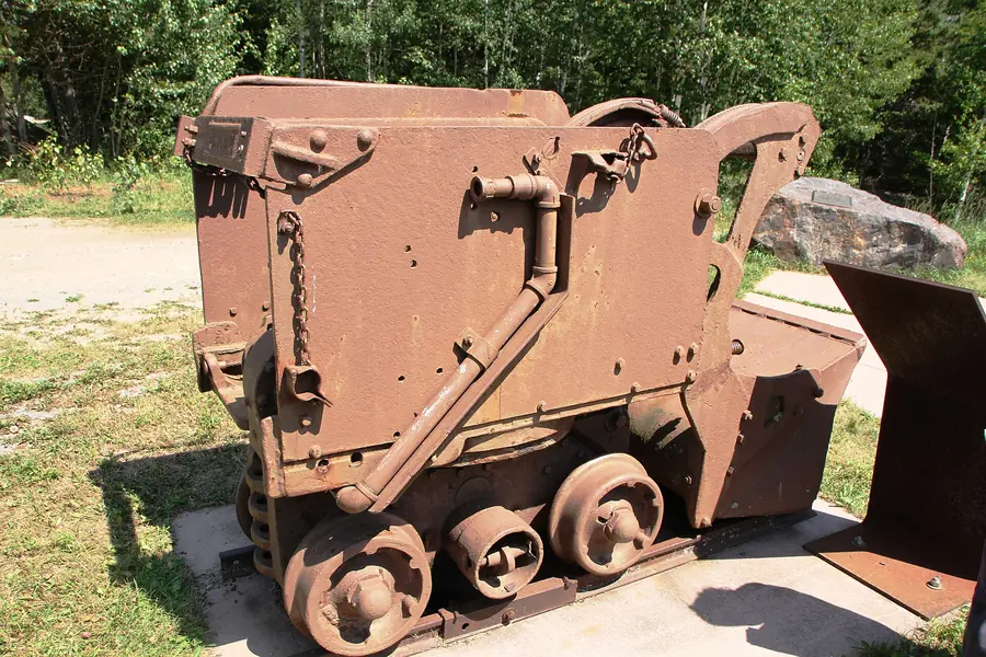 A rusty rail-mounted overshot loader on display outdoors