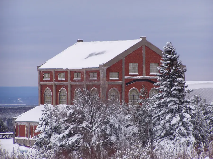 A red brick hoist house in the snow among spruce trees
