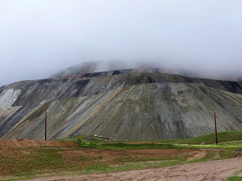 A huge grey waste dump under low cloud with green grass in front