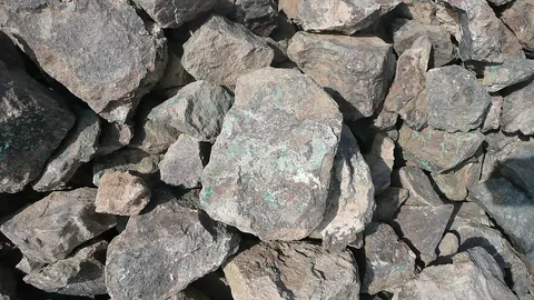 A pile of grey rocks with green copper staining